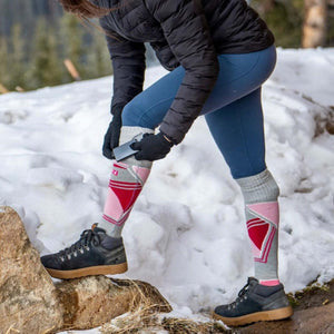 Person adjusting battery pack on heated socks while standing in snow