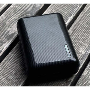 Black portable power bank with 10000mAh capacity on a wooden surface