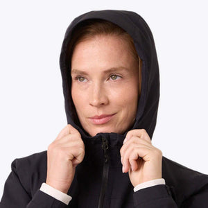 Woman wearing a black hooded jacket with hands pulling the hood edges