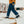 Person wearing dark blue denim jeans and black winter boots walking through snow