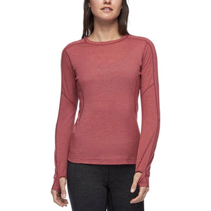 Woman wearing a red long sleeve crew neck base layer with thumb holes