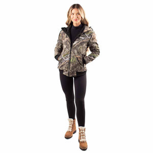 Woman wearing a camo Gobie Heat hooded jacket with black leggings and brown winter boots