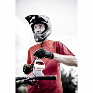 Cyclist wearing Hestra gloves and a full face helmet holding goggles