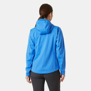 Back view of a woman wearing a blue Helly Hansen hooded rain jacket with black trousers