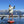 Person wearing Glacier Glove apparel paddle boarding on a lake with mountains in the background