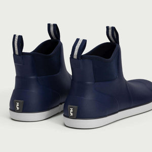 Rear view of navy blue Huk ankle boots with white soles and pull tabs