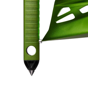 Close up of a green metal tent stake with a pointed black tip and a cutout design