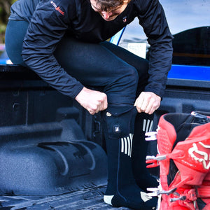Person wearing ActionHeat black heated socks while sitting in a truck bed