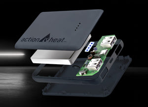 Exploded view of a dark grey 'action heat™' portable electronic device, revealing its internal white block, green circuit board with illuminated blue lights, and USB ports.