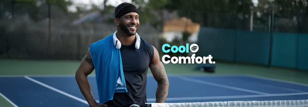 Smiling man in a black tank top, headband, and neck fan on a tennis court, a blue Alphacool towel over his shoulder. Text: Cool Comfort.