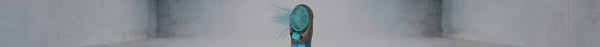 A teal and dark grey personal fan on the right emits bright blue streams into an empty, stark grey concrete room.