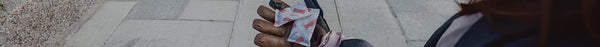 A person wearing a brown leather glove holds multiple white packets of 
