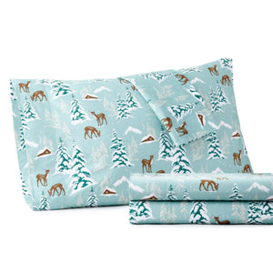 Light blue sheet set with a winter forest pattern featuring deer snow covered trees and cabins