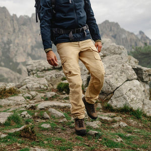 Person wearing Fjallraven beige cargo trousers and hiking boots on a rocky mountain trail