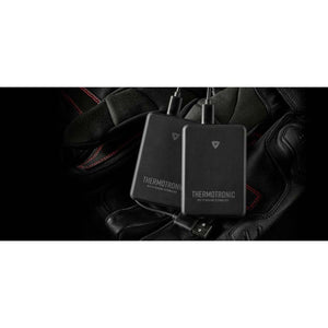 Two black REVIT Thermotronic heating technology battery packs resting on black leather gloves