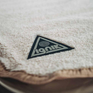Ignik triangular brand patch on textured cream fabric