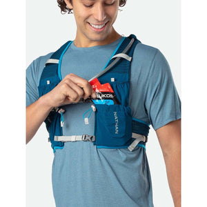 Person wearing a blue Nathan hydration vest while placing an energy gel into a front pocket