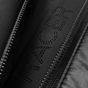 Close up of the word Racer perforated in black fabric next to a zipper