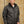 Man wearing a black Volt heated puffer jacket against a concrete wall