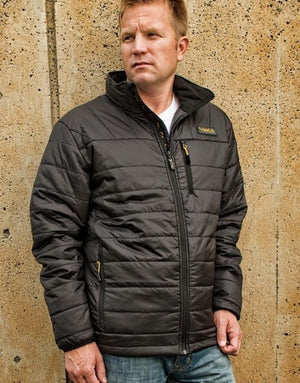 Man wearing a black Volt heated puffer jacket against a concrete wall