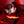 Woman sitting on a bed using a laptop with a red light therapy mat on her lap