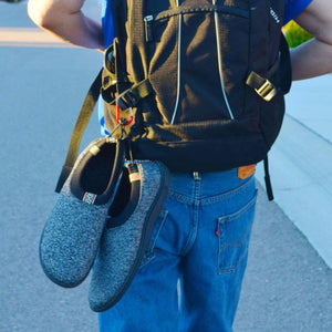 Grey slip on shoes clipped to a black backpack with a carabiner