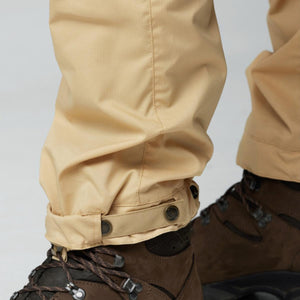 Close up of FjallRaven beige trouser hem with adjustable strap and buttons worn over brown hiking boots