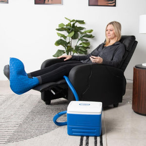 Person using a Polar Products cold therapy foot wrap while sitting in a recliner