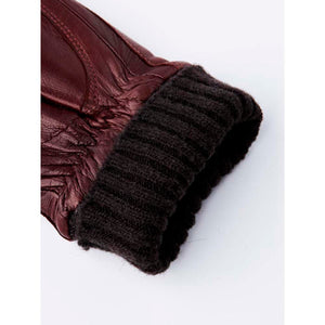 Close up of a burgundy leather glove with a dark brown ribbed knit cuff