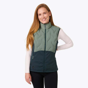 Woman wearing a two-tone green Mobile Warming heated vest over a white long sleeve shirt