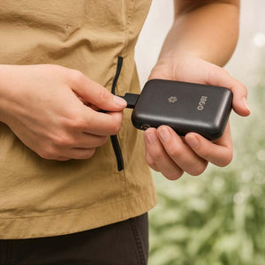 Person plugging a Gobi Heat portable power bank into a jacket pocket