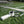 Portable neck fan with lanyard on a grass field with text overlays about cooling comfort and six hour duration