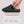 Hand inserting battery into grey heated slipper with battery life and temperature settings chart