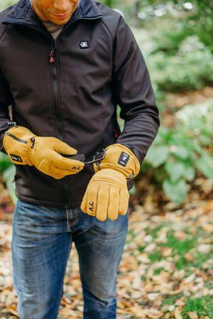 Person wearing ActionHeat tan suede heated gloves connecting a battery pack