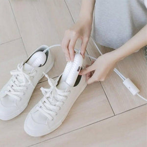 Person inserting white electric shoe dryer into white sneaker
