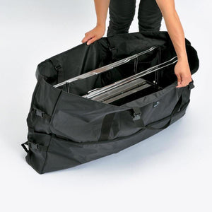 Person packing a Snow Peak storage bag with metal camping equipment