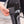 Hand pressing the power button on a black heated compression calf sleeve