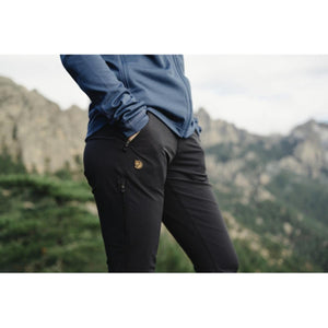 Person wearing black FjallRaven trousers with zippered pockets in a mountain landscape