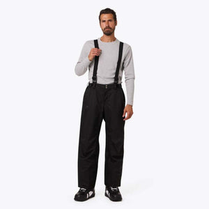 Man wearing Mobile Warming black snow pants with suspenders and a grey long sleeve shirt