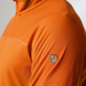 Close up of orange FjallRaven grid fleece fabric with branded logo patch on sleeve