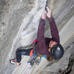 Climber wearing a Black Diamond helmet placing gear on a granite rock face