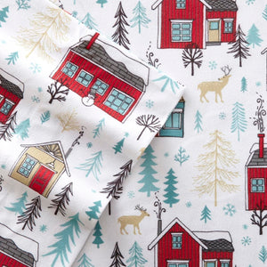 Fabric pattern featuring red houses, deer, and pine trees on a white background