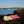 Acorn cream and pink plush flip flops on a rock by the water