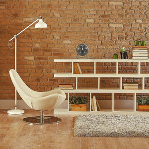 Small metal desk fan placed on a white bookshelf in a room with a brick wall
