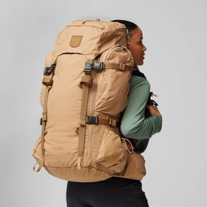 Person wearing a tan FjallRaven Kajka 55 backpack from the side