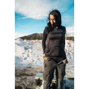 Woman wearing a black long sleeve quarter zip shirt and grey cargo pants standing in a snowy landscape