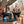 Couple sitting in camping chairs by a fire pit with Coleman cooler and mugs