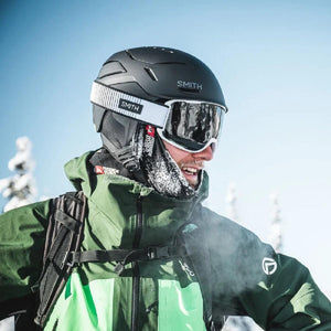 Person wearing a black Smith helmet and goggles with a green North Face jacket in a snowy environment