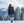 Woman wearing black puffer jacket blue leggings and patterned knee high socks standing in snowy mountain landscape