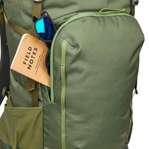 Kelty olive green backpack with a notebook and sunglasses tucked into the front pocket